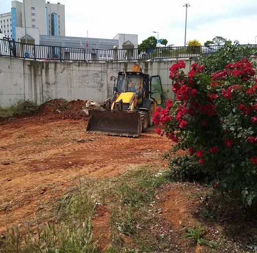 İstinat duvarı ve bahçe yanında çalışan kazıcı-yükleyici